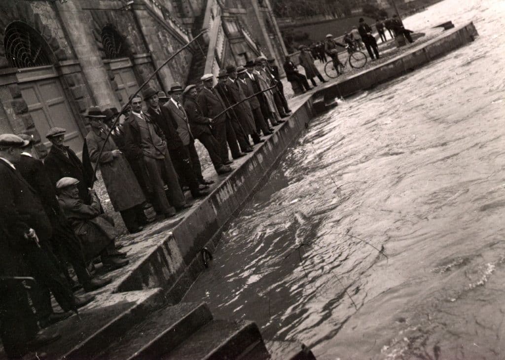 Pescatori ai Murazzi di lungo Po Cadorna con il fiume in piena, in una fotografia di Mario Gabinio.