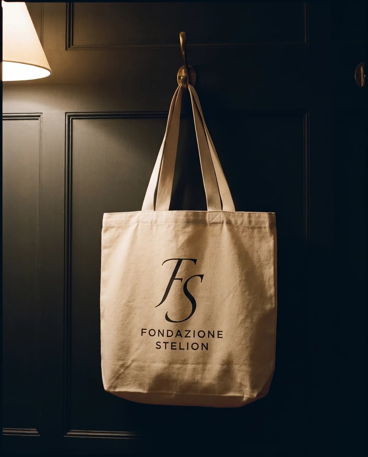 La borsa in tela di cotone grezzo portata a spalla, con il marchio stampato al centro.