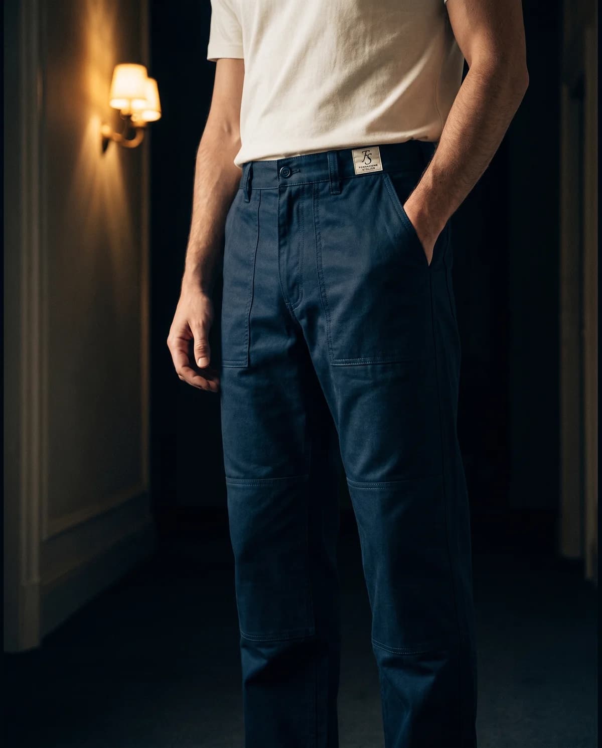I pantaloni da lavoro in cotone blu inchiostro indossati, con le cuciture doppie e il ginocchio rinforzato in vista.